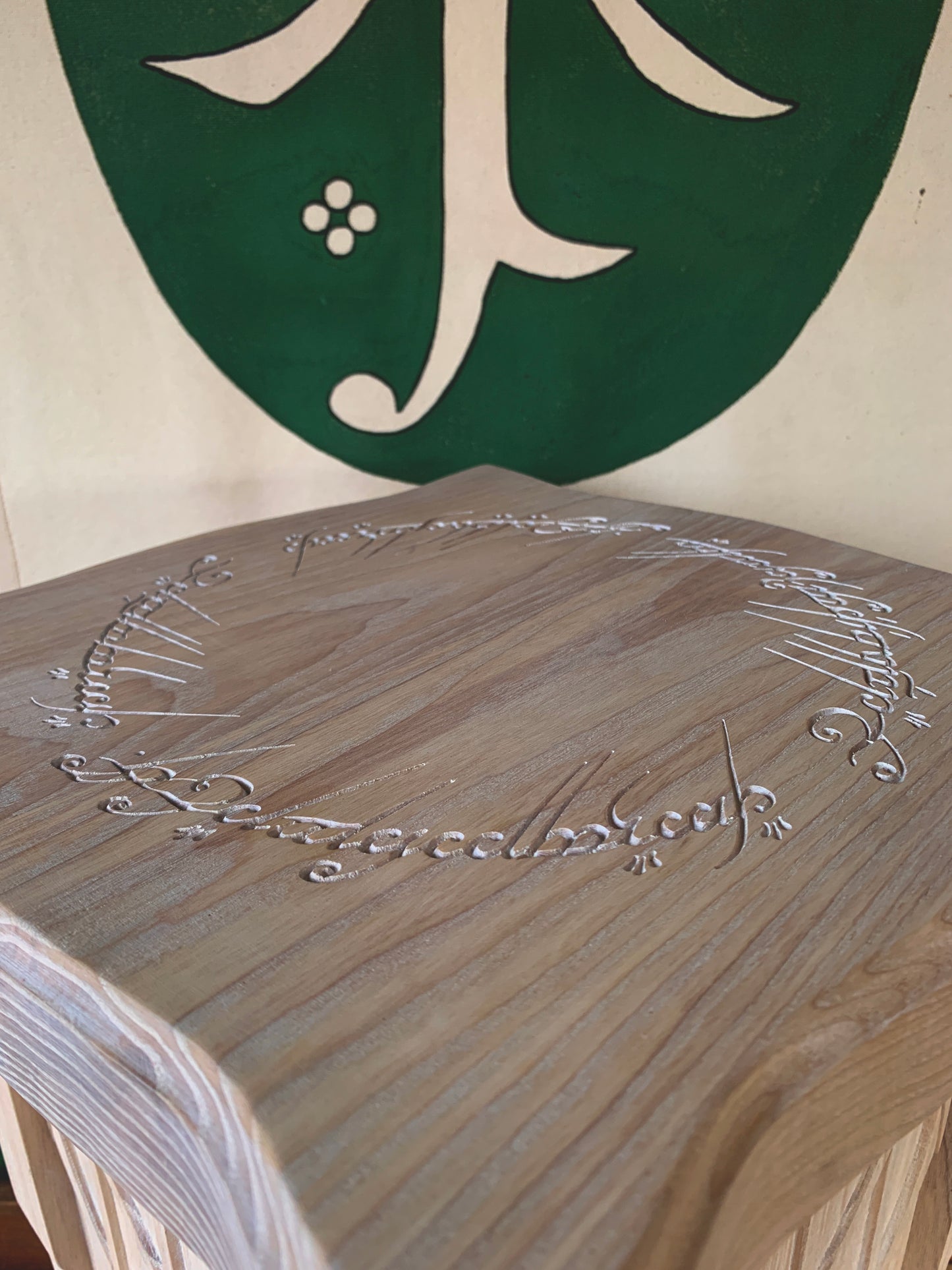 Closeup of ash wood side table with The One Ring text engraved on it
