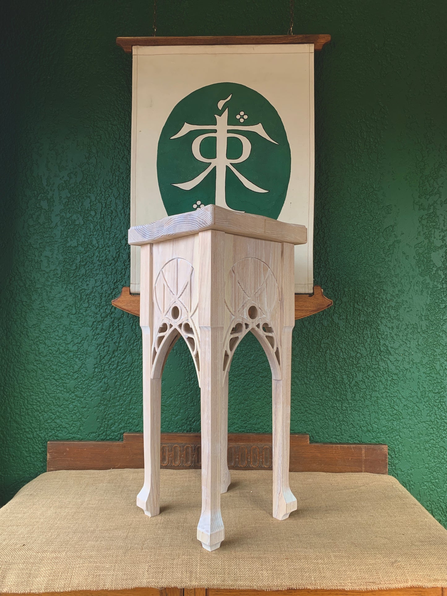Lord of the Rings ash wood side table with Rivendell arches. Green wall background with JRR Tolkiens sigil on a canvas banner.
